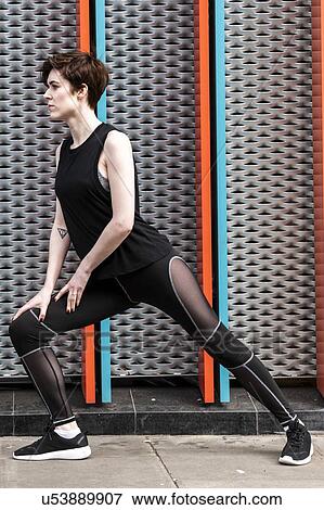 Stock Photo - Young woman practicing yoga pose on city sidewalk, full length. Fotosearch