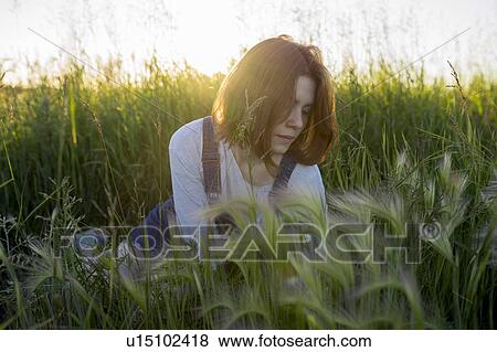 Young woman sitting in wheat field View Large Photo Image Stock Photo - Young woman sitting in wheat field. Fotosearch