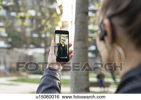 Young woman taking selfie with smartphone in city View Large Photo Image Stock Photograph - Young woman taking selfie with smartphone in city. Fotosearch