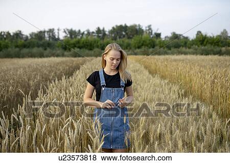Young woman wearing overall dress in wheat field View Large Photo Image Stock Photo - Young woman wearing overall dress in wheat field. Fotosearch