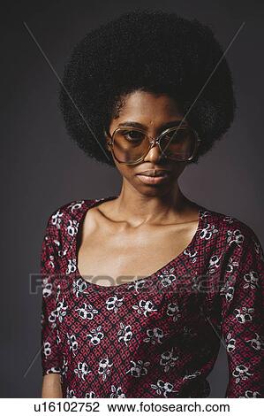 Young woman with afro hair against grey background View Large Photo Image Stock Image - Young woman with afro hair against grey background. Fotosearch