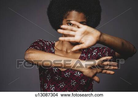 Young woman with afro hair covering face with hands, grey background View Large Photo Image Picture - Young woman with afro hair covering face with hands, grey background. Fotosearch