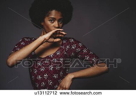 Young woman with afro hair covering mouth, grey background View Large Photo Image Stock Image - Young woman with afro hair covering mouth, grey background. Fotosearch