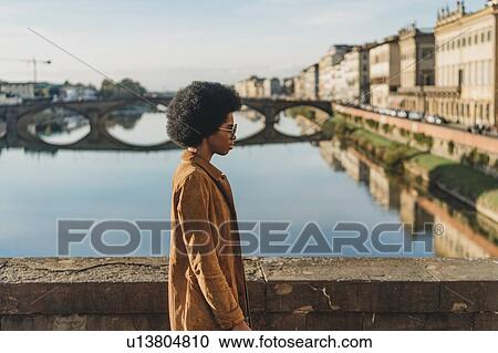Young woman with afro hair crossing bridge, Florence, Toscana, Italy View Large Photo Image Stock Image - Young woman with afro hair crossing bridge, Florence, Toscana, Italy. Fotosearch