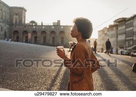 Stock Photo - Young woman with afro hair exploring city, Florence, Toscana, Italy. Fotosearch