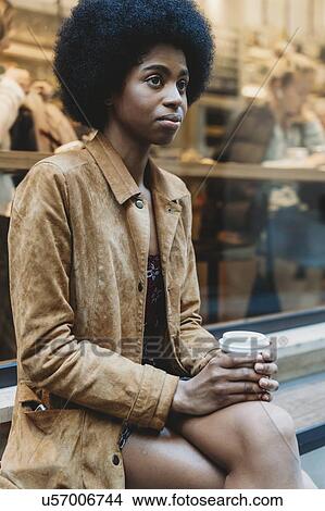 Young woman with afro hair having hot drink in front of cafe View Large Photo Image Picture - Young woman with afro hair having hot drink in front of cafe. Fotosearch