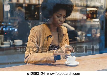 Young woman with afro hair having coffee in cafe View Large Photo Image Picture - Young woman with afro hair having coffee in cafe. Fotosearch