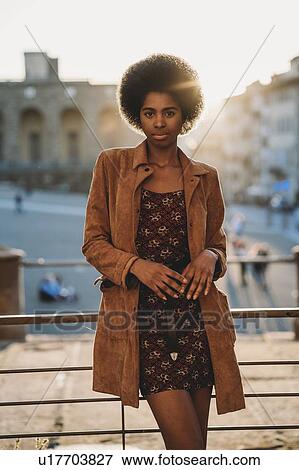 Stock Photo - Young woman with afro hair leaning against handrail, Florence, Toscana, Italy. Fotosearch