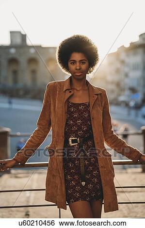 Stock Photograph - Young woman with afro hair leaning against handrail, Florence, Toscana, Italy. Fotosearch