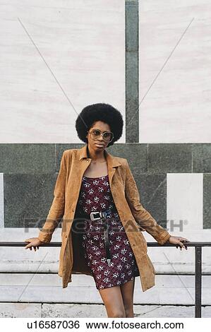 Young woman with afro hair resting against handrail in city View Large Photo Image Stock Photograph - Young woman with afro hair resting against handrail in city. Fotosearch