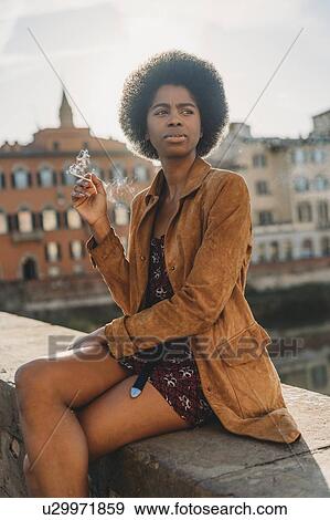 Young woman with afro hair smoking on bridge, Florence, Toscana, Italy View Large Photo Image Stock Photo - Young woman with afro hair smoking on bridge, Florence, Toscana, Italy. Fotosearch