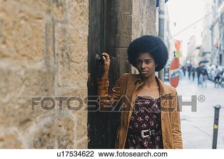 Young woman with afro hair waiting at door of stone building View Large Photo Image Stock Image - Young woman with afro hair waiting at door of stone building. Fotosearch