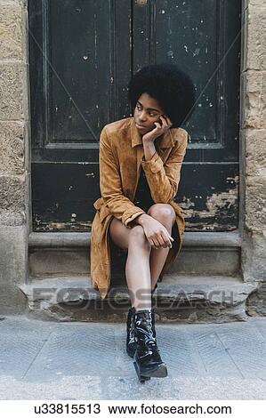 Young woman with afro hair waiting at door of stone building View Large Photo Image Stock Image - Young woman with afro hair waiting at door of stone building. Fotosearch