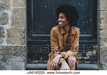Young woman with afro hair waiting at door of stone building View Large Photo Image Stock Photography - Young woman with afro hair waiting at door of stone building. Fotosearch