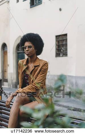 Young woman with afro hair waiting in front of building View Large Photo Image Stock Photograph - Young woman with afro hair waiting in front of building. Fotosearch
