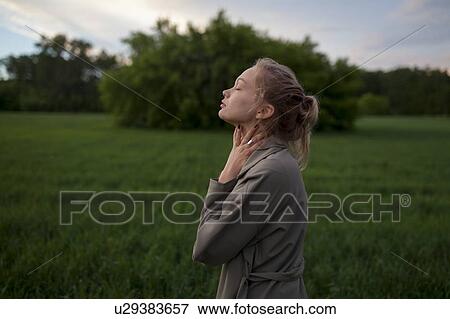 Stock Photo - Young woman with her eyes closed in field. Fotosearch