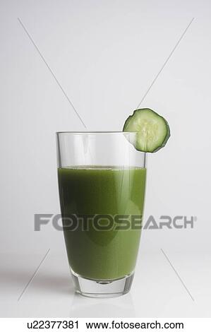 Stock Image - A glass of fresh green juice with a slice of cucumber. Fotosearch