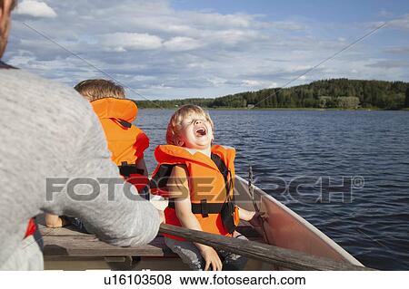 Stock Photo - Adult sailing with excited boys on boat in lake, Finland. Fotosearch