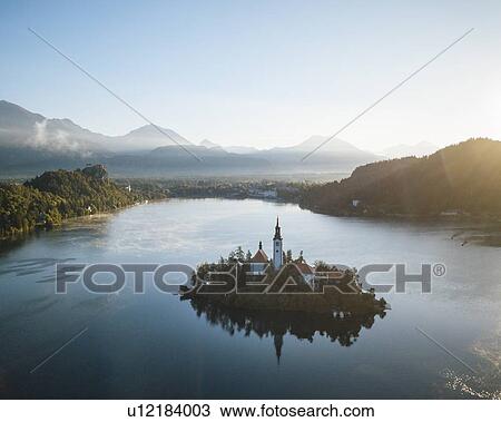 Stock Image - Aerial view of Bled Island with Church of the Assumption at dawn, Lake Bled, Upper Carniola, Slovenia. Fotosearch
