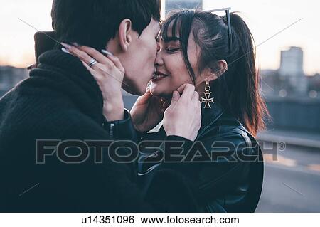 Stock Photograph - Affectionate young couple on street, Milan, Italy. Fotosearch