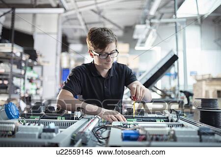 Stock Photography - Apprentice electronics engineer in electronics assembly factory. Fotosearch