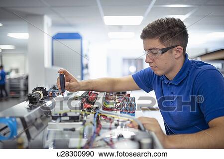 Stock Image - Apprentice engineer assembling laboratory cabinet on production line in medical scientific factory. Fotosearch