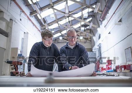 Stock Image - Apprentice with mentor engineer in mould making department in steelworks. Fotosearch