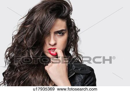 Stock Photo - Attractive female biting finger on lips. Fotosearch