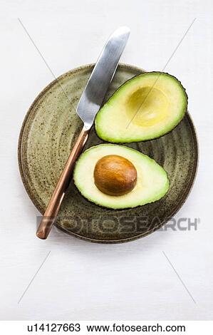 Stock Image - Avocado cut in half on a plate. Fotosearch