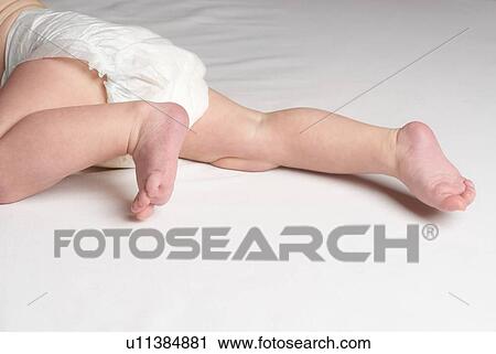 Stock Image - Baby crawling on bed close up of feet. Fotosearch