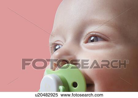 Stock Photography - Baby girl with pacifier against pink background. Fotosearch