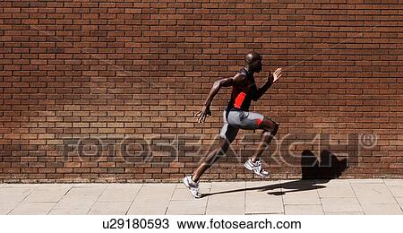 Stock Image - Black male Athlete Sprinting on Sidewalk. Fotosearch
