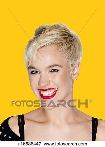 Stock Photo - Blond Young Woman smiling against yellow background. Fotosearch