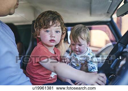 Stock Image - Boy and baby sister sitting in car with father. Fotosearch