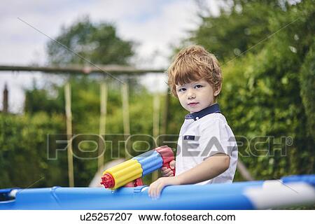 Boy holding water gun by pool View Large Photo Image Stock Photo - Boy holding water gun by pool. Fotosearch