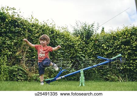 Boy hopping off toy seesaw in garden View Large Photo Image Stock Photography - Boy hopping off toy seesaw in garden. Fotosearch