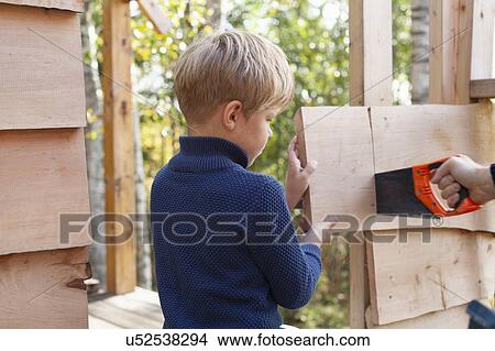 Picture - Boy learning to build treehouse with adult. Fotosearch
