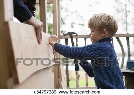 Stock Photo - Boy learning to build treehouse with adult. Fotosearch