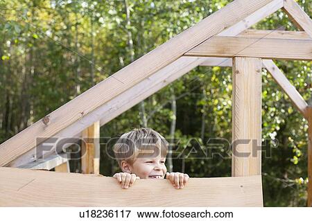 Boy peering from unfinished treehouse View Large Photo Image Stock Photo - Boy peering from unfinished treehouse. Fotosearch