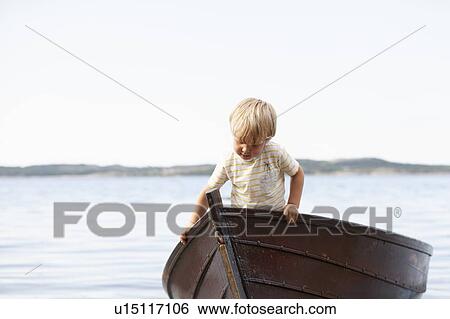 Stock Photograph - Boy playing in boat on beach. Fotosearch