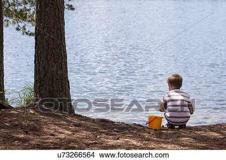 Picture - Boy playing near lake. Fotosearch
