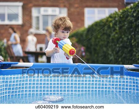 Boy playing with water gun by pool View Large Photo Image Stock Photo - Boy playing with water gun by pool. Fotosearch
