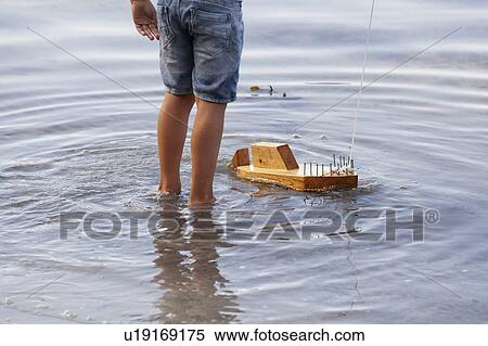 Boy playing with wooden toy boat in water View Large Photo Image Stock Photography - Boy playing with wooden toy boat in water. Fotosearch