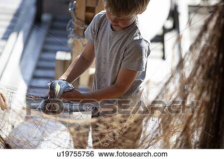 Boy removing fish from fishing net View Large Photo Image Stock Photograph - Boy removing fish from fishing net. Fotosearch