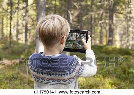 Stock Image - Boy taking photograph of forest. Fotosearch