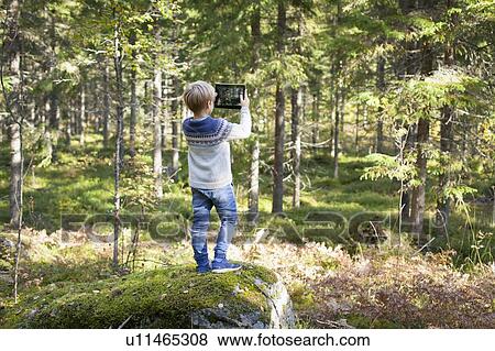 Stock Photo - Boy taking photograph of forest. Fotosearch