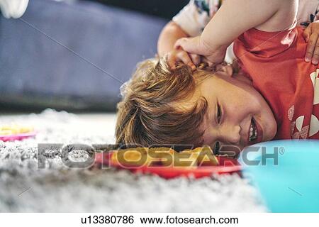 Stock Photograph - Boys play-fighting during meal on rug. Fotosearch
