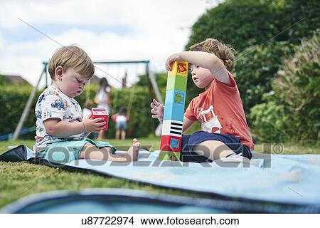 Brother and baby sister playing with blocks on picnic blanket View Large Photo Image Picture - Brother and baby sister playing with blocks on picnic blanket. Fotosearch