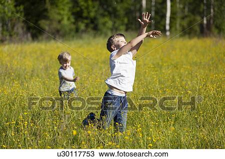 Stock Image - Brothers exploring and playing in meadows. Fotosearch