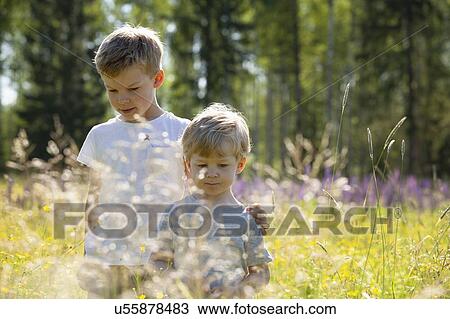 Stock Image - Brothers exploring and playing in meadows. Fotosearch
